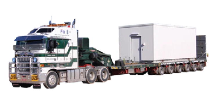 A large white and green semi-truck is hauling a long flatbed trailer carrying a white rectangular portable building.